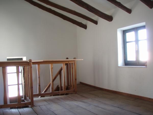 the bedroom has a window and a sloping open beamed ceiling